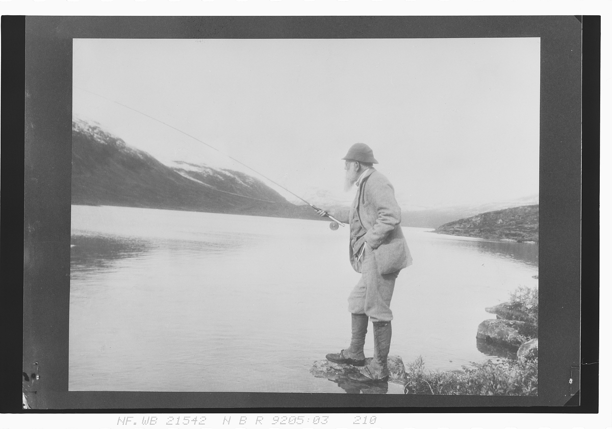 Mann står å fisker, Fernely. Fotografert 1927.