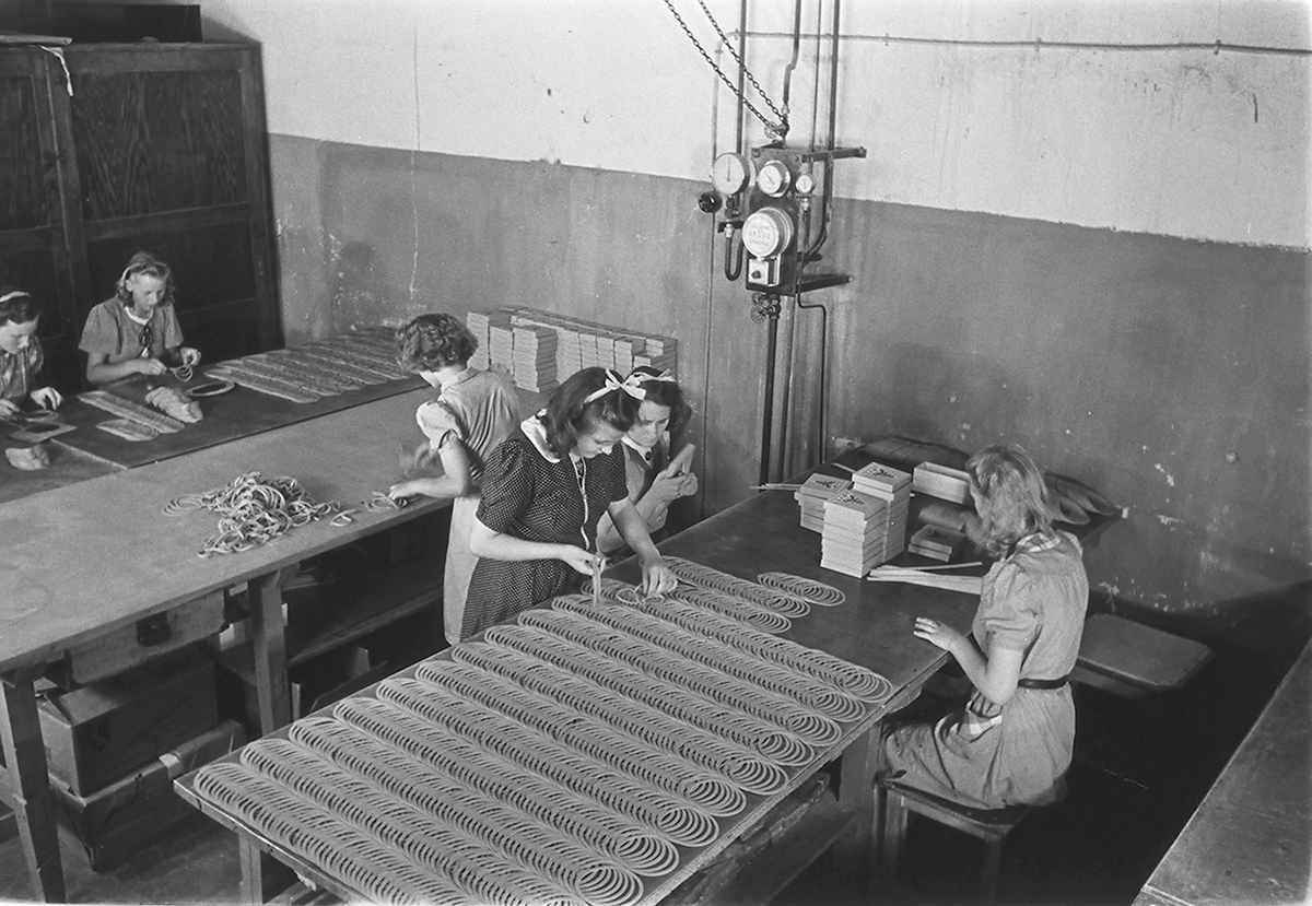 Ansatte i produksjonshallen. Den Norske Kalosje- & Gummivarefabrikk A/S, senere Mjøndalen Gummivarefabrikk, Eiker. Fotografert 1940.