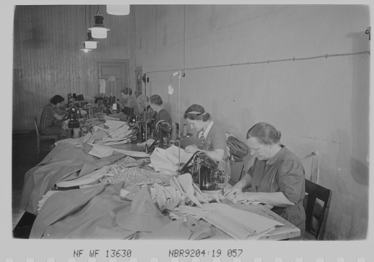 Kvinnelige ansatte i produksjon av gummitøy. Den Norske Kalosje- & Gummivarefabrikk A/S, senere Mjøndalen Gummivarefabrikk, Eiker. Fotografert 1940.