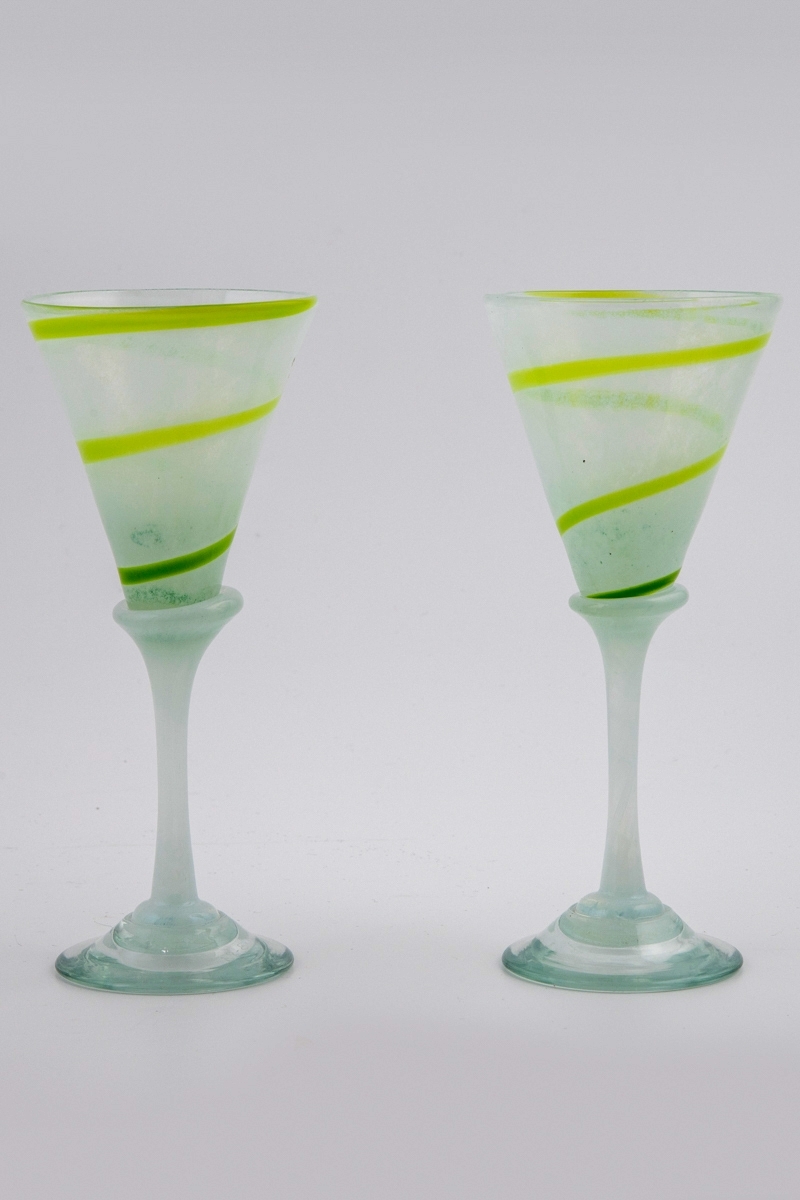 To glass i halvgjennomskinnelig glass. Kupa er melkehvit og dekorert med en grønn spirallinje. Overgangen til den melkehvite stetten er markert med en skjev vulst. Fotplaten er utført i klart glass.