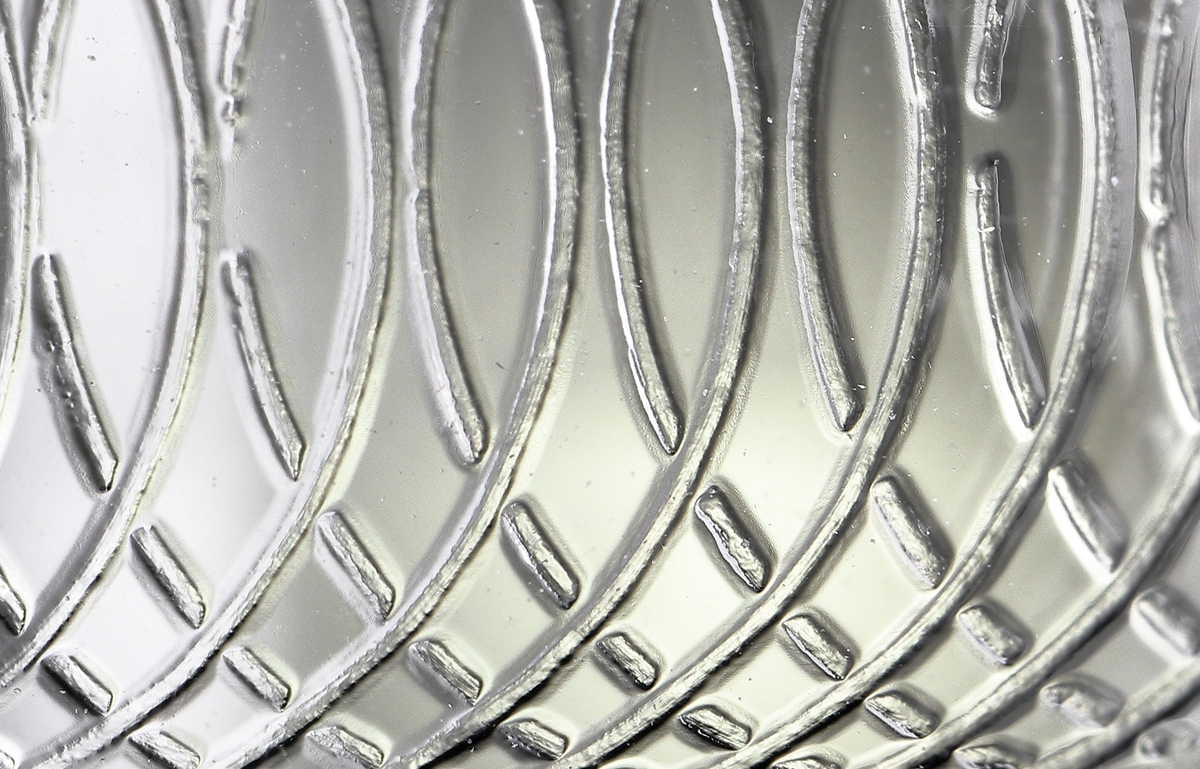 Glas (R.275).
Beskrivning: Guillocherad eller pantograferad bård.
Färg: Ofärgat klarglas.
Mått: Diameter ovan avser glasets fotdiameter.
Inskrivet i huvudkatalogen 1942.
Funktion: Servisglas