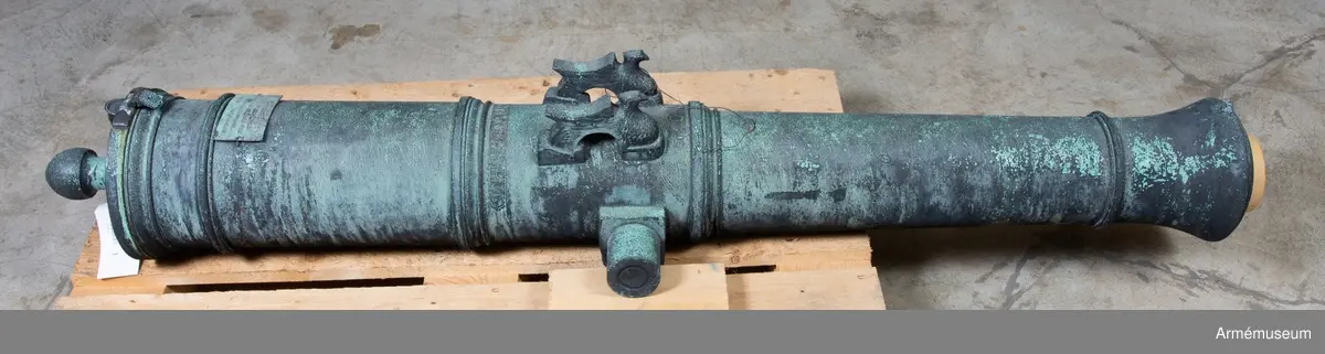 Med årtalet 1803 strax framom och inskriften: "St. Petersburg", å ryska, strax bakom delfinerna.

På den vänstra tappens fria ände: "No 98", på den högra tappens fria ände: 20 pu  27 fu  - "20 Pud 27 Funt". Fängpannan har formen av ett manshuvud utan skägg, och befinner sig på bottenplanet. /v. Tepfers.

Märkt på tappstycket med 1803.