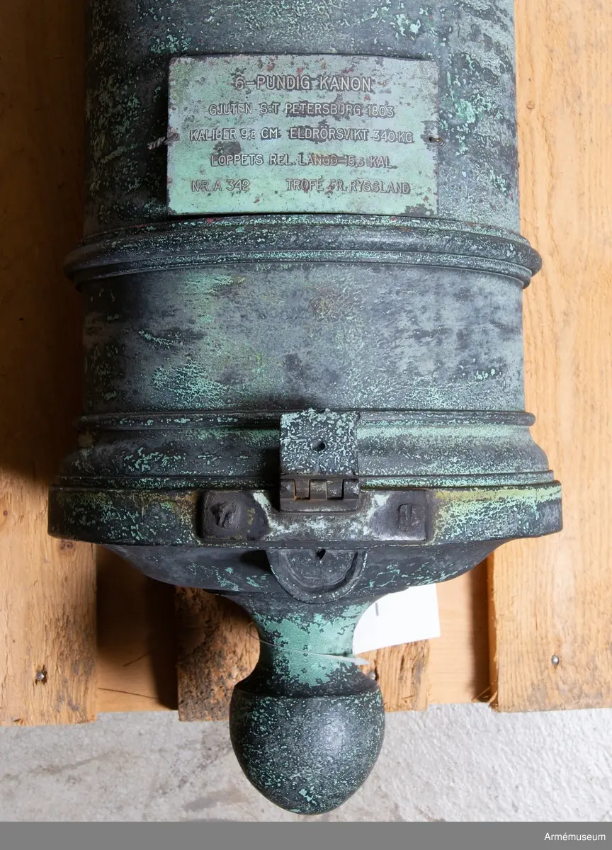 Med årtalet 1803 strax framom och inskriften: "St. Petersburg", å ryska, strax bakom delfinerna.

På den vänstra tappens fria ände: "No 98", på den högra tappens fria ände: 20 pu  27 fu  - "20 Pud 27 Funt". Fängpannan har formen av ett manshuvud utan skägg, och befinner sig på bottenplanet. /v. Tepfers.

Märkt på tappstycket med 1803.