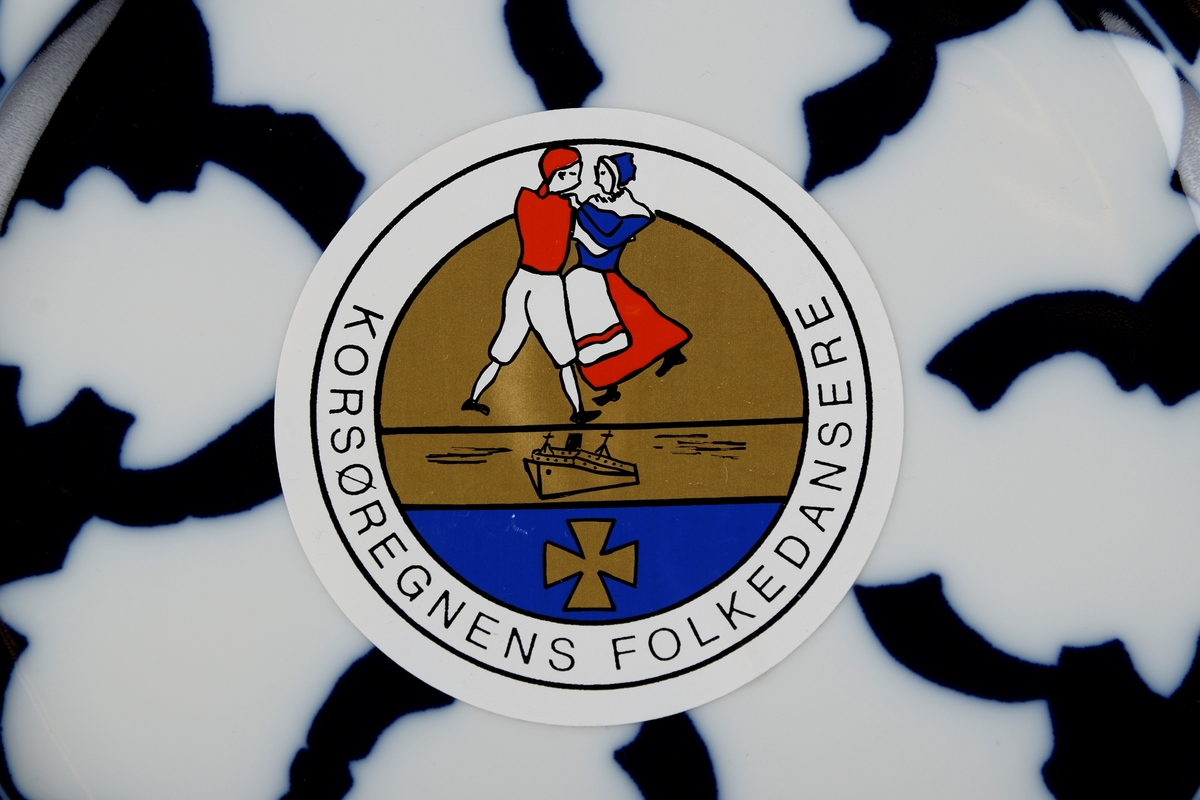 Et dansende par, et skip og et malteserkors. Logoen til Korsøregnens Folkedanslag.