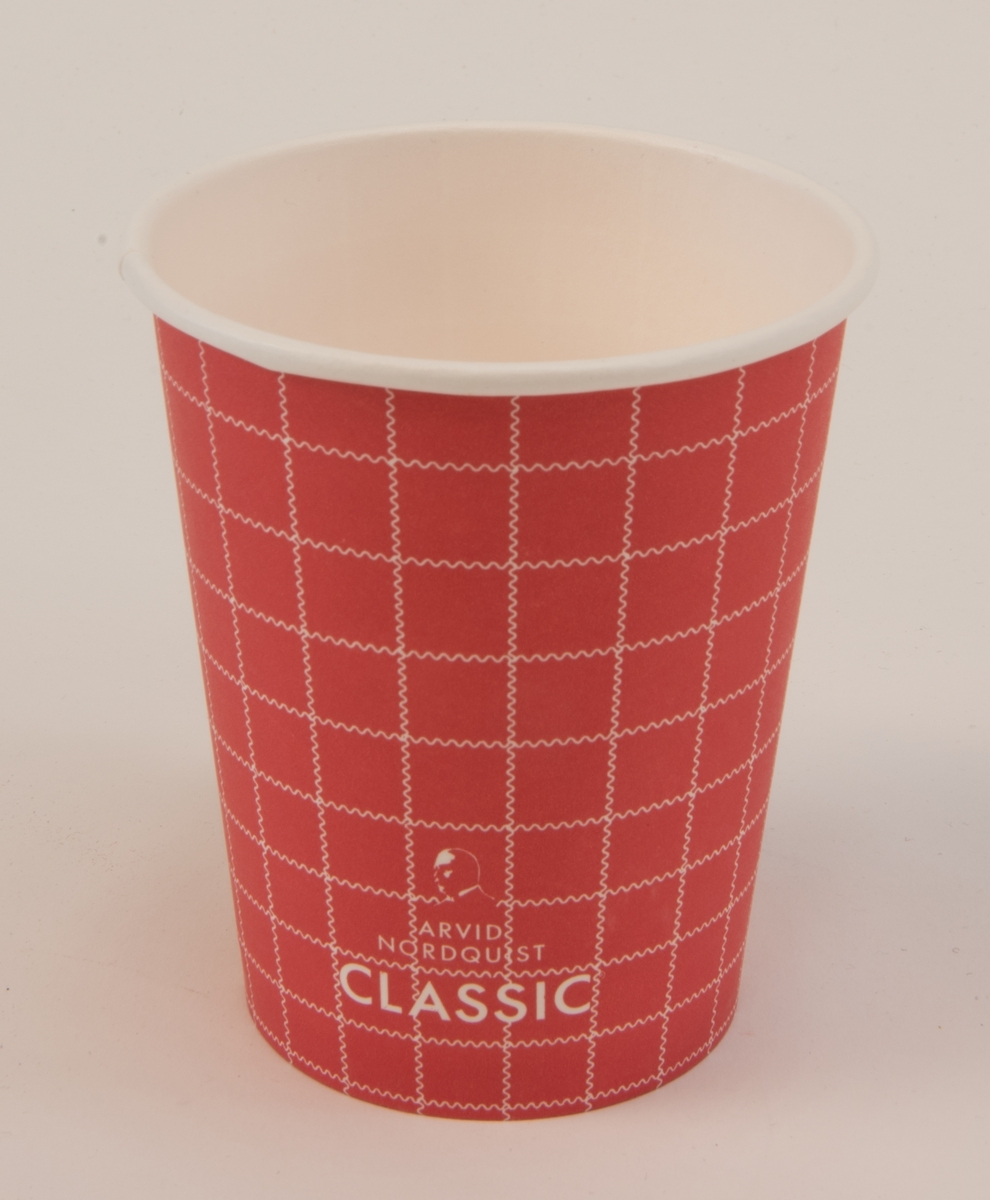 Pappersmugg för engångsbruk (:1), utvändigt röd med vitt rutmönster, med löstagbart vitt plastlock (:2). De vita ränderna som bildar rutmönstret är vågiga. På muggens ena sida står det "SJ BISTRO" och på andra sidan reklam för kaffemärket Arvid Nordquist Classic. På plastlocket finns tre stycken runda välvda "knappar" som går att aktivera för att ange om kaffet är koffeinfritt (decaf), innehåller mjölk eller grädde (cream) eller är svart (black). På locket finns även tillverkarens namn "Tingstad".