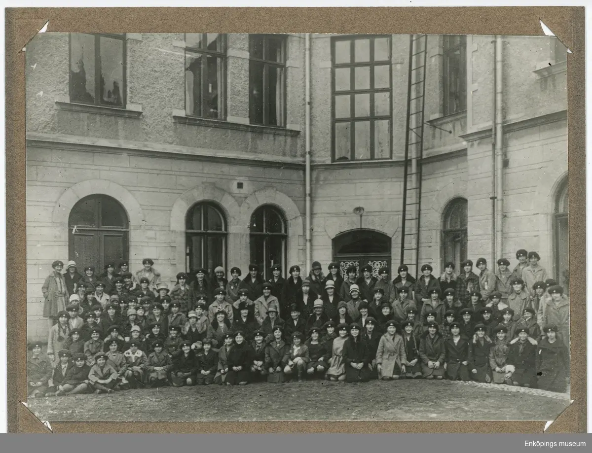 Tavla med inramat fotografi.
Fotografiet föreställer flickor från Elementarskolan för flickor, Enköping, läsåret 1928–29. De står förmodligen på innergården vid gamla Sparbankshuset.
Dr. Ernst Westerlund var initiativtagare till Elementarskolan för flickor. Skolan startades den 1 september 1885. Dr. Westerlund donerade skolmaterial, möbler, hyrde skollokal och donerade pengar till skolan. Han var även hälsoansvarig på skolan och gav eleverna kostnadsfri sjukvård. Skolan lades ned 1935.
Den sista bilden visar ett tidningsurklipp från Enköpings-Posten den 8 juni 1886 där dessa fakta framkommer.