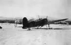 Flygplan Saab B 17 står på ett snötäckt fält i Gällivare, 1944. I bakgrunden syns fjället Dundret. Vy bakifrån. Under övning i Gällivare.