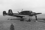 Flygplan Saab J 21A tillhörande F 8 Barkarby på ett flygfält, 1940-tal. Vid vingen står en flygmekaniker.