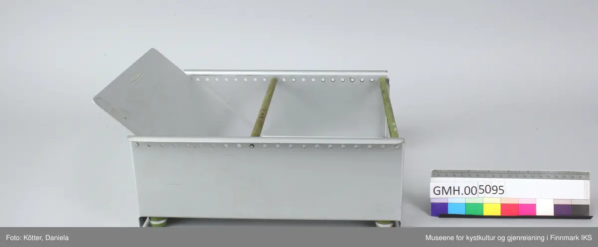 Trauet har en bunn og to sider av aluminium. Sidene er foran og bak forbundet med stenger. Imellom er det en stang som kan flyttes Det følger også med en skillevegg som kan settes i slisser i bunnen.