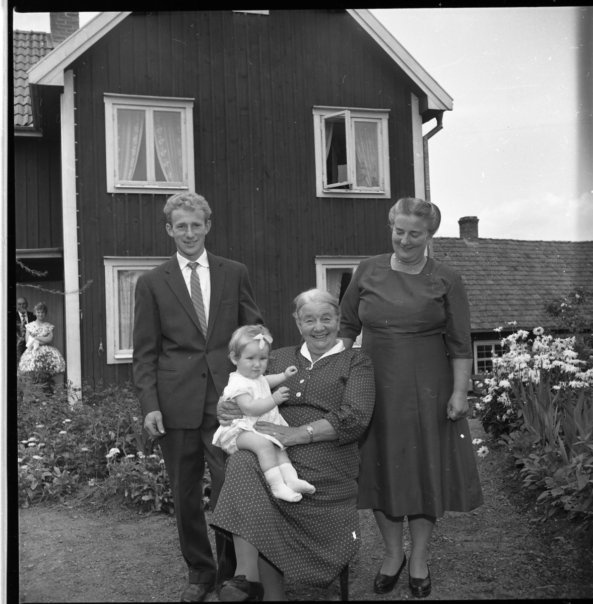 Fyra generationer samlade på gårdsplan till en fastighet i Kaxtorp. Ester Karlsson sitter med en liten flicka knät. Bakom henne står dottern Britta Granstrand och till vänster hennes barnbarn Sten Egon Granstrand.