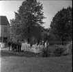 Konfirmander på väg in till Gränna kyrka med kyrkoherde Wallis Wendel i täten. Utmed Brahegatan i bakgrunden skymtar en fastighet med skylten 