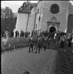 Manliga konfirmander på väg ut ur Gränna kyrka. En folksamling uppe vid trappan.