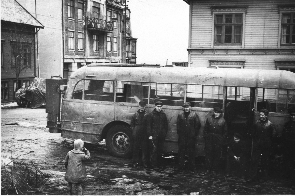 Menn foran buss med knottgenerator ved verkstedet til Harstad Bilsalg A/S i Erlings gate. Unge i forgrunnen, Grand i bakgrunnen til venstre.