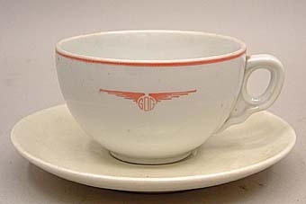 Kaffekopp från GDG av vitt porslin med röd dekor. Röd rand upptill och GDG:s logotyp på sidan, i form av deras initialer mellan ett par vingar.