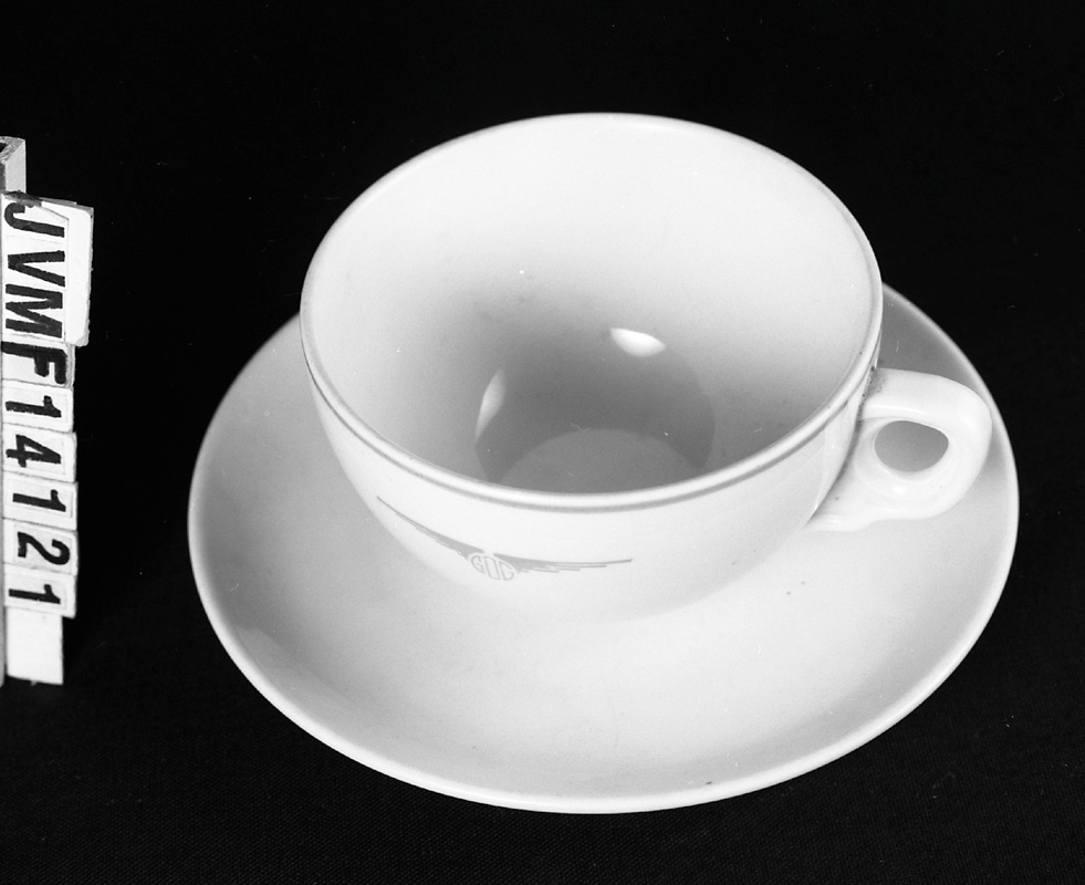 Kaffekopp från GDG av vitt porslin med röd dekor. Röd rand upptill och GDG:s logotyp på sidan, i form av deras initialer mellan ett par vingar.