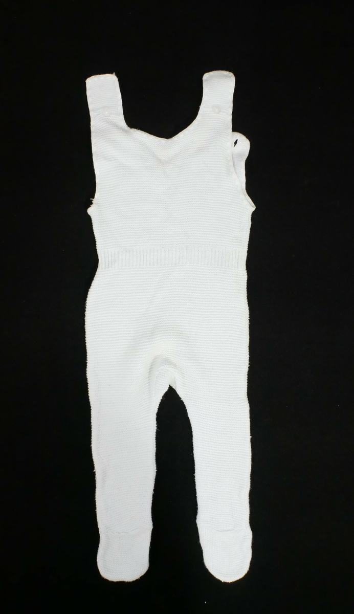 Bukse med fot. Kile i skrittet.Rundklipt i halsen med knepping på kvar side. Markering med vrangbord i livet, mønsterstrikk på overdelen
