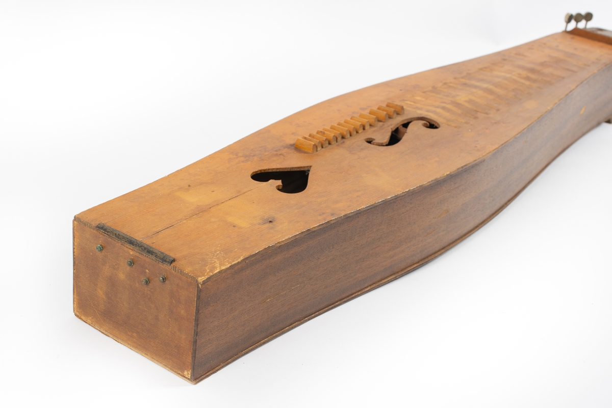 Utbuktende kropp med konvekse sidestykker. Skruekasse med rett brett i forlenging av kroppen. Seks stemmeskruer (gitar/mandolin-skruer) av metall. Tverrbjelke under lokket, synlig gjennom lydhull. Enkelt f-lydhull og et hjerteformet lydhull. 15 tverrband (mangler). 13 noter ved siden av f-lydhull. D-dur. Notesadel oppe og nede (mangler). Strenger (mangler): 1 melodi, 5 bodun. Vurdert strengefeste, ni hakk på notesadel nær stemmeskruene, fem på nedre ende. Fire metallfester på nedre endevegg. Ben oppe og nede (mangler). 
Lite eller ingen bruksmerker/slitasje etter spill.