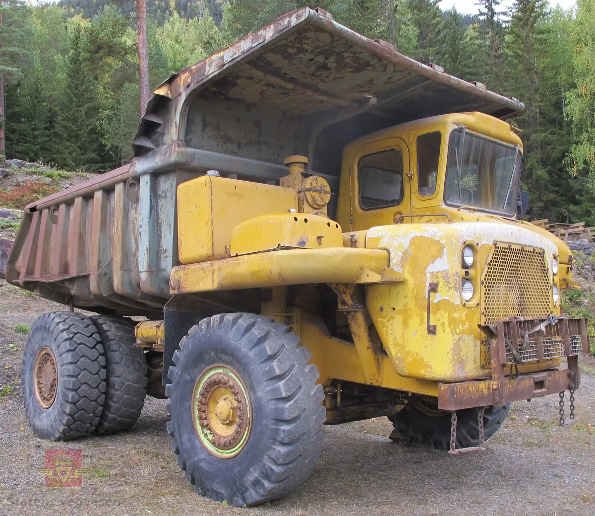 35 tonns gul dumper med 6 hjul, 2 akslinger. Tvillinghjul på bakaksel. 6-sylindret 14,6 liters Caterpillar dieselmotor som yter 400 hk. Dumperkassen har et volum på 17,8 m³. Skiltplater med serienummer 99F986 plassert på rammen og motoren. Metallplater fra produsenten med smørekart og advarsler. Hytte og motordeksler er i glassfiber. Dumperens toppfart er på 69 km/t.