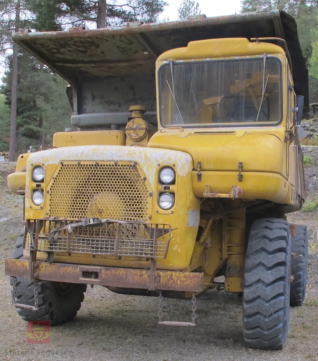 35 tonns gul dumper med 6 hjul, 2 akslinger. Tvillinghjul på bakaksel. 6-sylindret 14,6 liters Caterpillar dieselmotor som yter 400 hk. Dumperkassen har et volum på 17,8 m³. Skiltplater med serienummer 99F986 plassert på rammen og motoren. Metallplater fra produsenten med smørekart og advarsler. Hytte og motordeksler er i glassfiber. Dumperens toppfart er på 69 km/t.