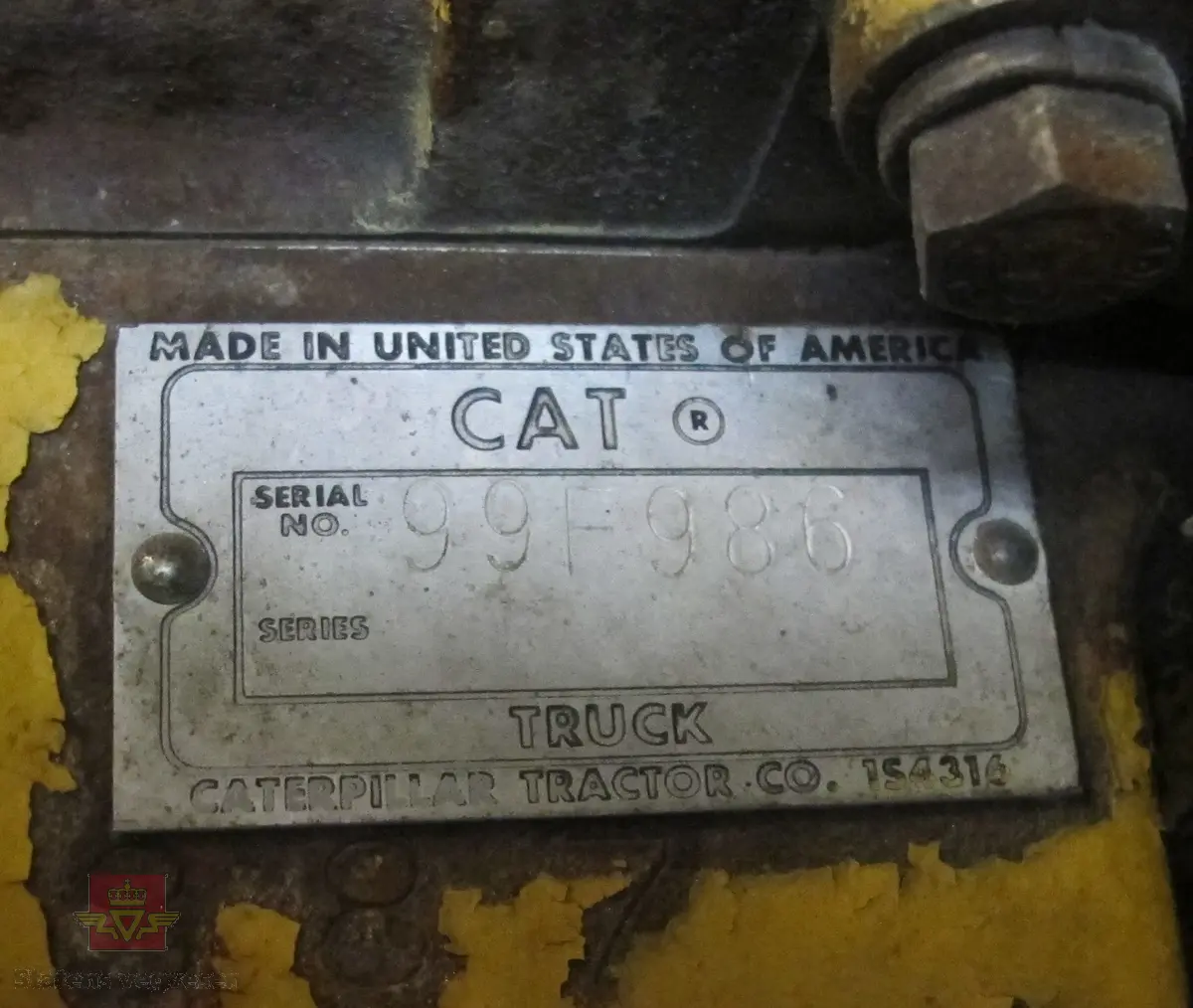 35 tonns gul dumper med 6 hjul, 2 akslinger. Tvillinghjul på bakaksel. 6-sylindret 14,6 liters Caterpillar dieselmotor som yter 400 hk. Dumperkassen har et volum på 17,8 m³. Skiltplater med serienummer 99F986 plassert på rammen og motoren. Metallplater fra produsenten med smørekart og advarsler. Hytte og motordeksler er i glassfiber. Dumperens toppfart er på 69 km/t.