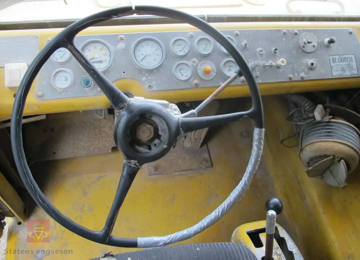 35 tonns gul dumper med 6 hjul, 2 akslinger. Tvillinghjul på bakaksel. 6-sylindret 14,6 liters Caterpillar dieselmotor som yter 400 hk. Dumperkassen har et volum på 17,8 m³. Skiltplater med serienummer 99F986 plassert på rammen og motoren. Metallplater fra produsenten med smørekart og advarsler. Hytte og motordeksler er i glassfiber. Dumperens toppfart er på 69 km/t.