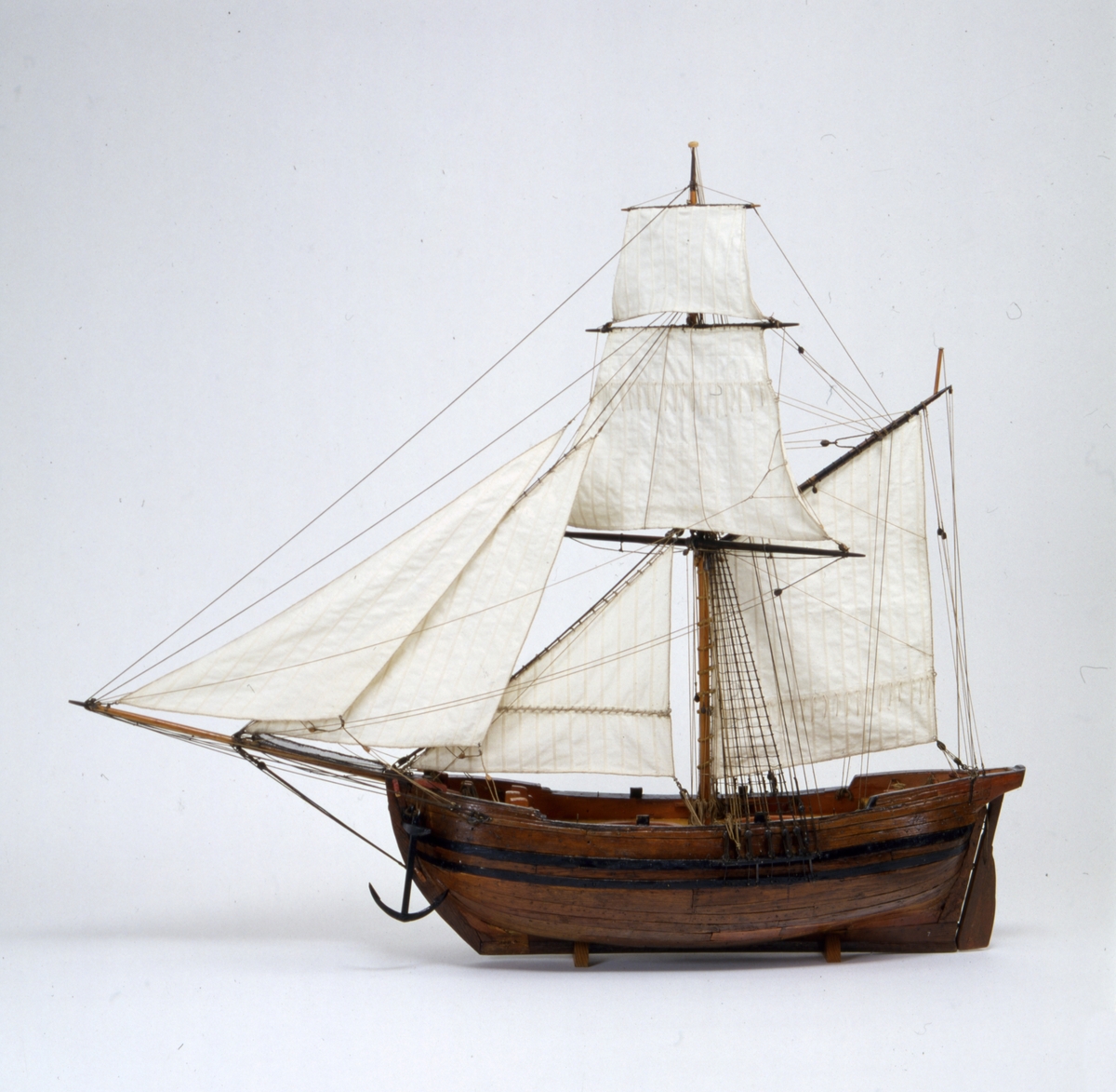 Båtmodell, gigg, bordlagd på spant, kravell, med fullständig inredning. Roder med rorkult . 9 st årtullar. 9 st åror. Fernissad med röd reling, svart sugband.   Åror, bänkar och sittrum rödmålade. Innerbotten och trall fernissade. Stativ brunmålat.