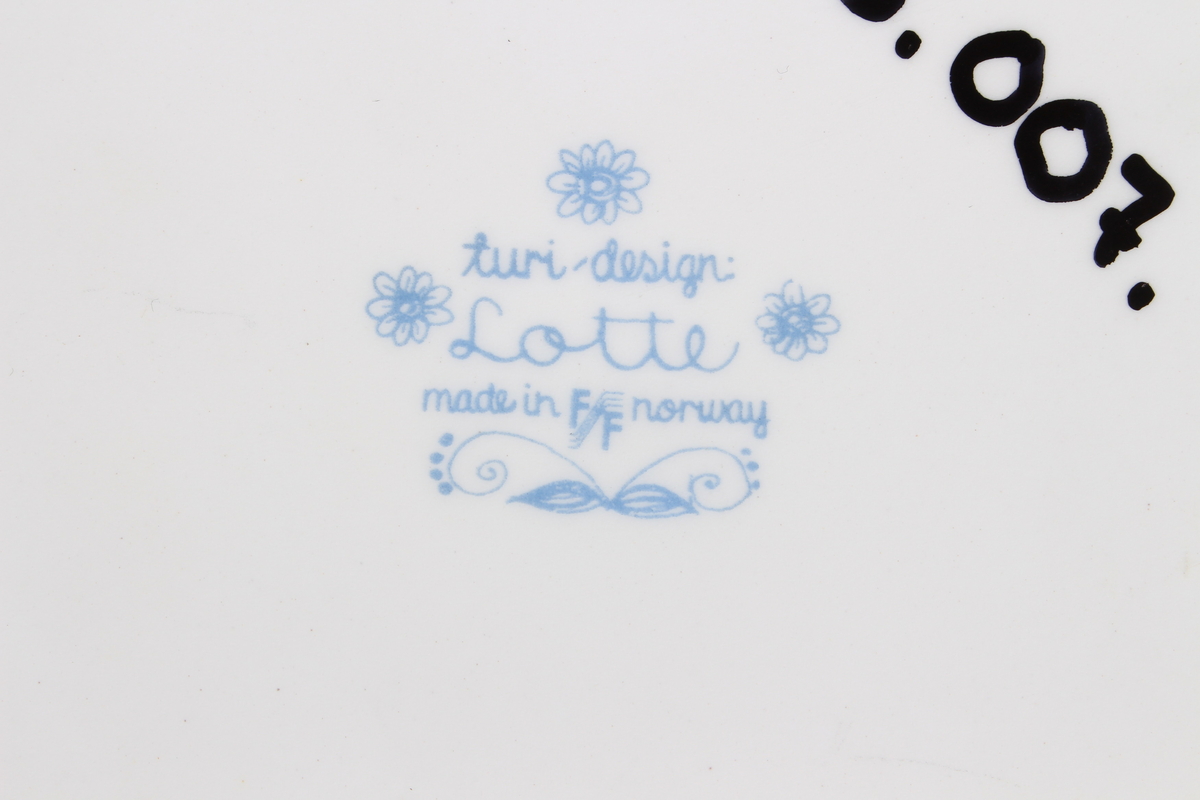 Tallerkene er dekorert med et bilde av en mann  og en kvinne som har blader og blomster på seg og rundt seg. De to menneskene er glade og de danser i blader og blomster.