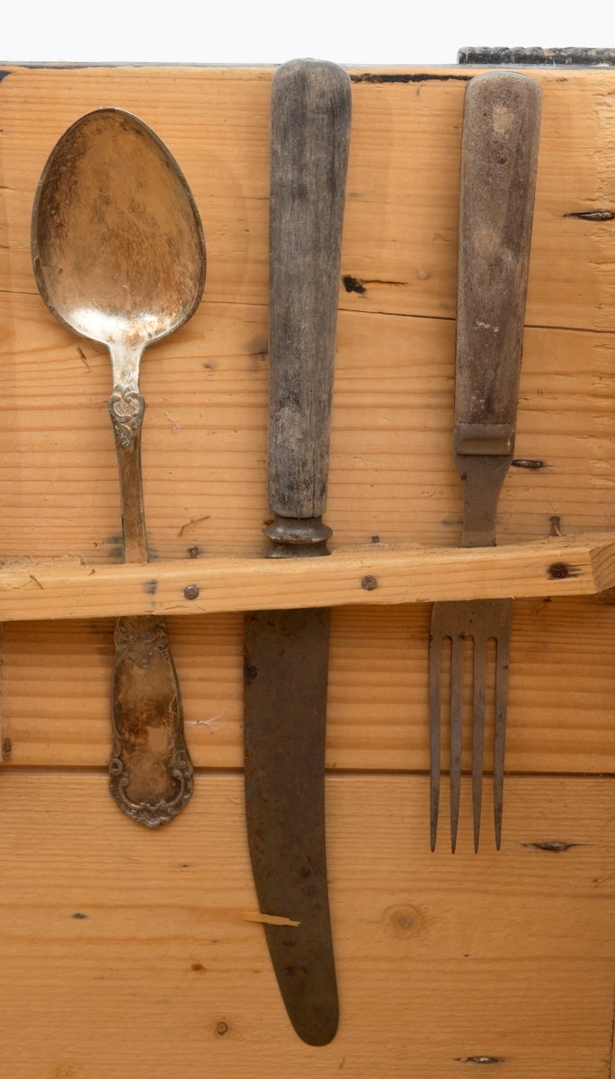 Trekasse, brukt som mat- eller proviantkasse i situasjoner der eieren måtte oppholde seg flere døgn utmarka, for eksempel under hogst eller tømmerfløting. Dette kan ha vært ei trekasse som opprinnelig ble lagd som emballasje ved vareforsendelser, og som sekundært lett modifisert med tanke på nevnte bruksformål. Kassa er lagd av forholdsvis tynne, høvlete granbord. I botnen. I botnen og på langsidene er bordtjukkelsen 10 millimeter, i tverrendene 13 millimeter og i lokket kun 8 millimeter. Botnflata er 47,5 centimeter lang og 36 centimeter bred. Sideveggene er cirka 29,5 centimeter høye. Botnen, som er fastsikret på undersida, er ikke inkludert i dette måltallet, Langs kantene av endeveggene er det påsatt labankbord, noe som har gjort det enklere å spikre sammen sideveggene i hjørnene. Sentralt på den øvre delen av endeveggene er det - antakelig sekundært - påsdpikret knekter som skulle holde lokket på plass. Lokket er retangulært, 47,4 X 36,9 centimeter. Det holdes ihop av 4,8 centimeter brede labankbord, drøyt 4 centimeter fra tverrendene, og av et tverrstilt trehandtak på midten, med et cirtka 9 centimeter langt, gjennombrutt hull som eieren av matkassa kunne gripe i. Sentralt på tverrendene av lokket er det rektangulære innsnitt, tilpasset knektene i tverrenden av kassedelen. Disse innsnittene er blikkbeslåtte. Inni kassa, mot den ene tverrveggen, er det påspikret ei kort lekt med spalter for kniv, gaffel og skje. Innvendig her kassa trekvit. Yttersidene av sideveggene og oversida av lokket er innsatt med svart maling, muligens med et islett av grønt. Knektene øverst på endeveggene må skyves noe utover når lokket løftes av.