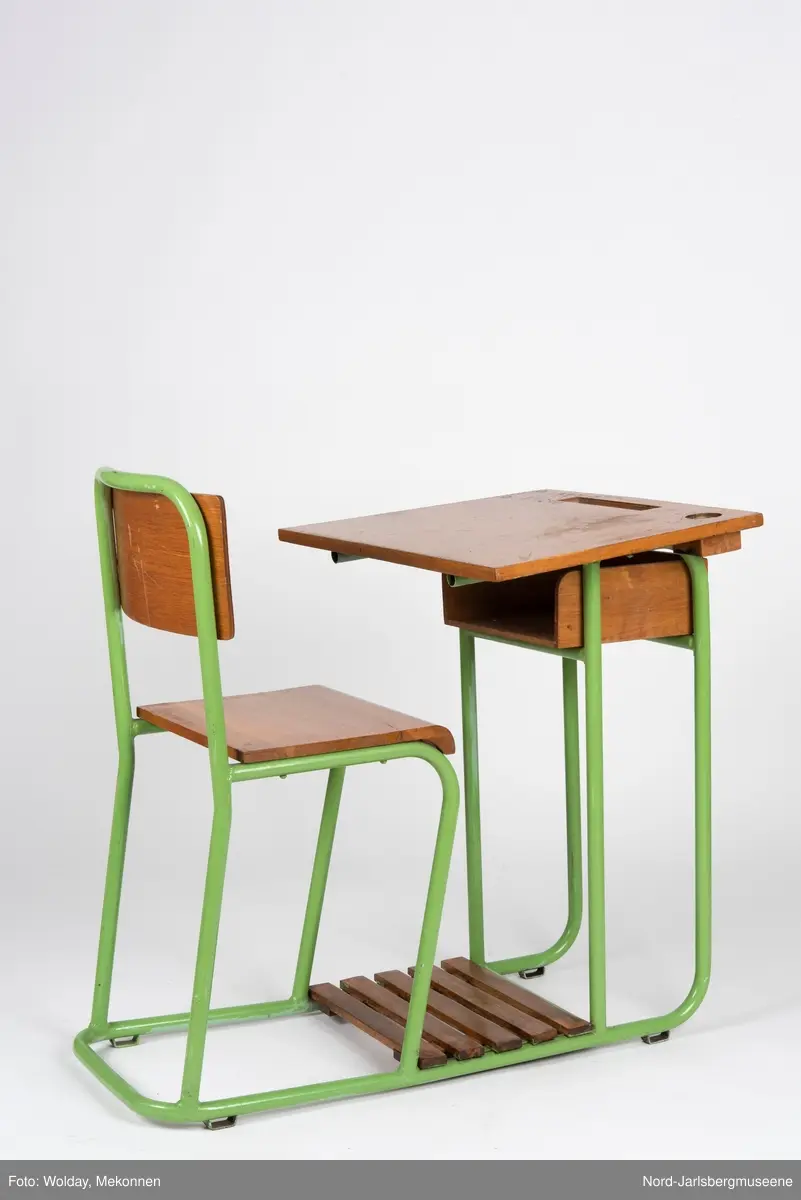 En sammenhengende stol-bord til en person. Stol- og bordbein av metallrør, sete, ryggstø og bordplate av finer.