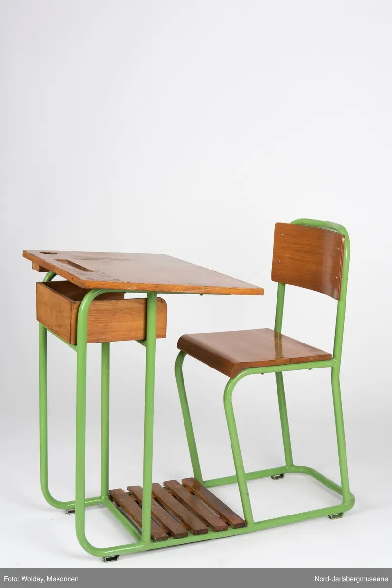 En sammenhengende stol-bord til en person. Stol- og bordbein av metallrør, sete, ryggstø og bordplate av finer.