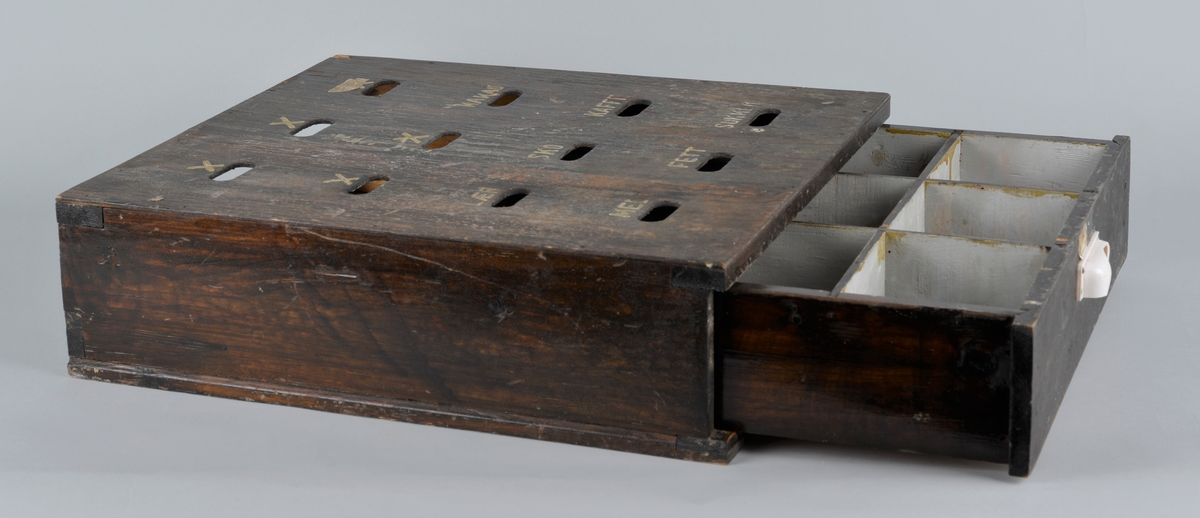 Trekasse for oppbevaring av rasjoneringskort, brukt under og etter andre verdenskrig.
Kassen har en uttrekkbar skuff med flere rom som passer til åpningene i fronten. Håndtaket på skuffen er delvis knust.
Kassen har 12 åpninger i 4 rekker, der det er påmalt tekst: 
1 rekke: X -  X - X 
2 rekke: X - X - kakao
3 rekke: lær - sko - kaffe
4 rekke: mel - fett - sukker