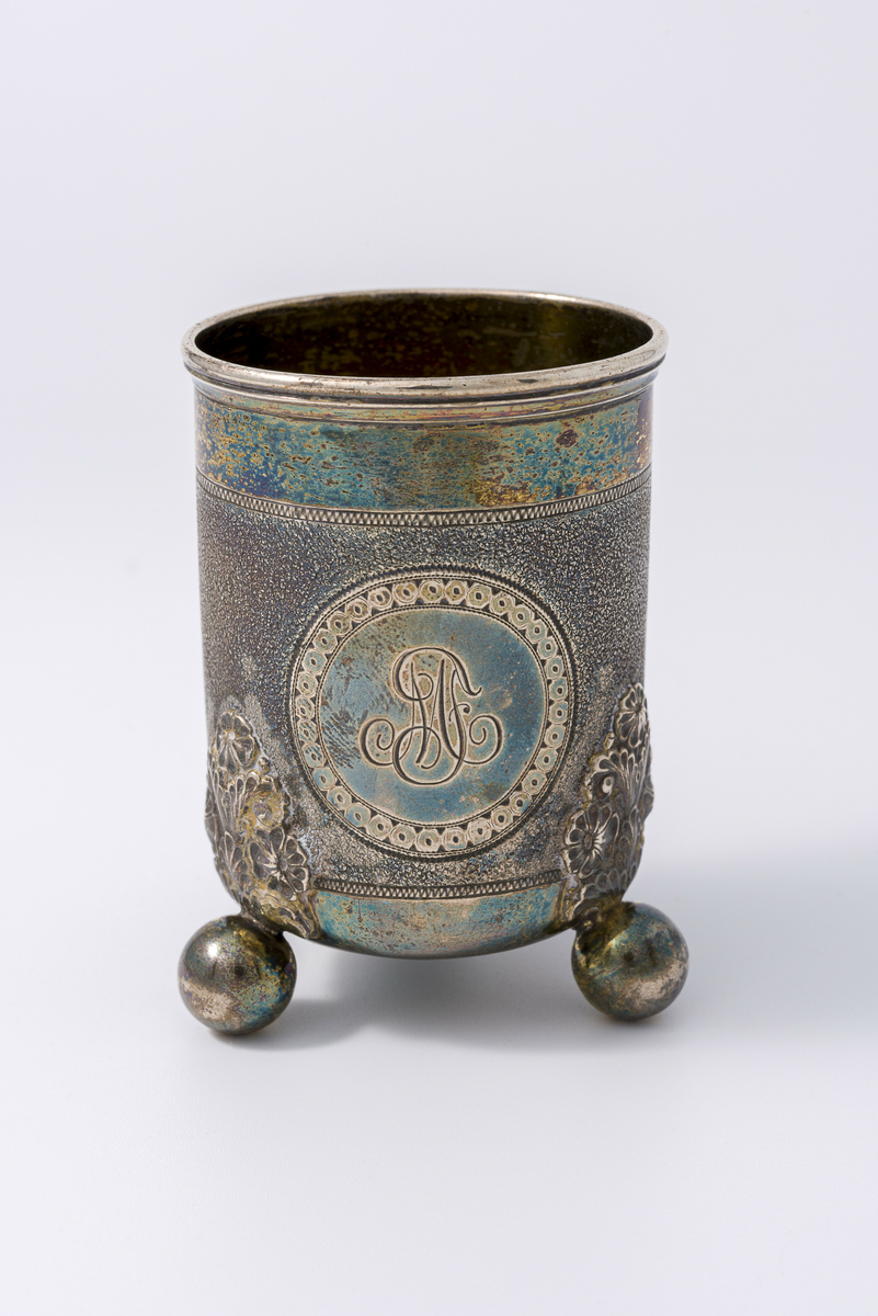 Beger i sølv med dekor. Tre støtter i bunn. Er produsert av gullsmed Tostrup, trolig i 1880. Har tilhørt Sara Fabricius. Initialene MF på begeret kan tyde på at det før har tilhørt hennes mor, Marga Fabricius (født. Anna Margareta (“Marga”) Greger).