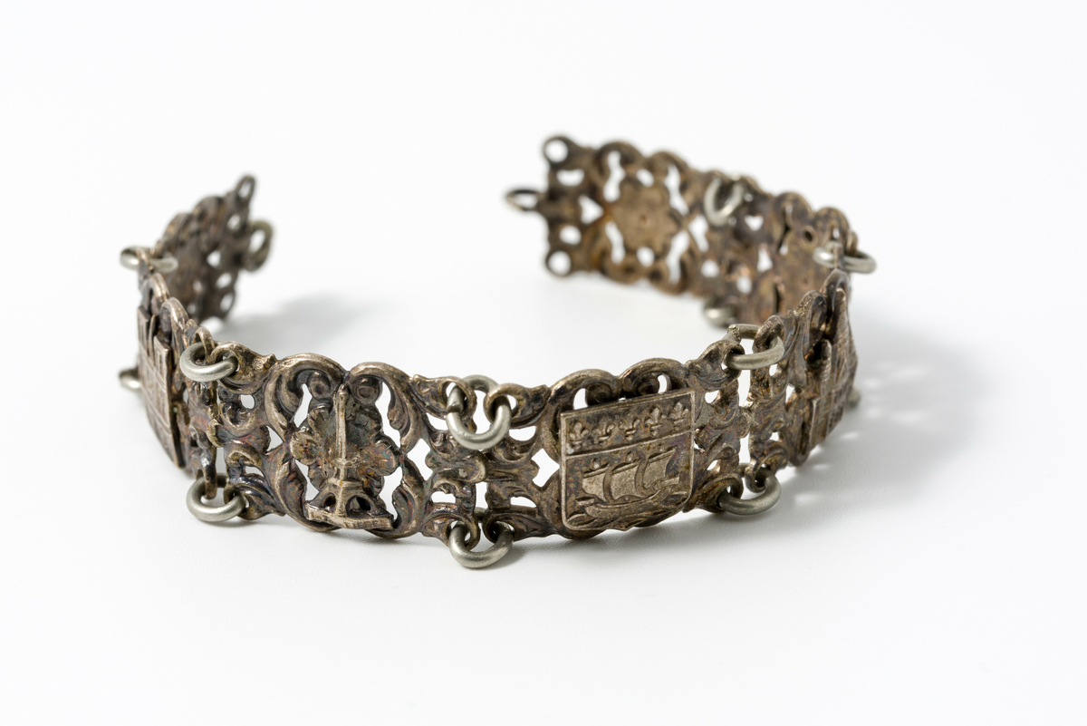 Armbånd i metall dekorert med motiv av blomster og kulturminner/landemerker (f.eks. eiffeltårnet og triumfbuen)