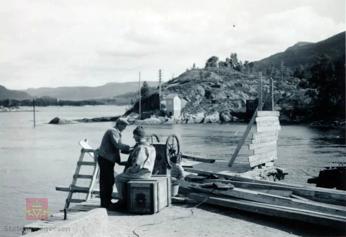 Usikkert hva dette motivet er, men formentlig er det fundamentet til brua som ble bygget høsten 1875 over Dragsundet mellom Hareidlandet og Gurskøya. Brua ble sener erstattet av ei Rullebru i 1912 og en en lang armert betongbru i 1953. 

Motivet kan også vise maskineriet som sveivet brua bygd i 1912 over sundet.

Brua fra 1875 var en kombinasjon av vippebru (heisebru) og skyvebru med en åpning på ca 7,5 meter. Til vanlig var sundet åpen for båttrafikk, og ble bare stengt når noen hadde bruk for bru. I første halvår 1878 ble det lagt bru 1693 ganger.