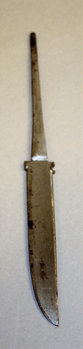 Bladet er kløyvstælt, og elles fint utforma og klargjort for montering i ein holka staskniv. Lang tange med rund avslutting, men ikkje gjenga. Bladet er uslipa utan stempel, men med smellopp.