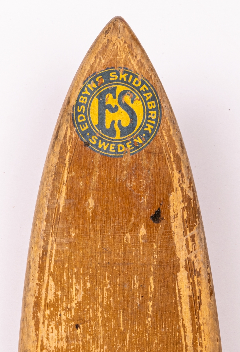 Ett par träskidor med bindningar i metall (rostiga). Märke påklistat med "Edsbyns Skidfabrik".