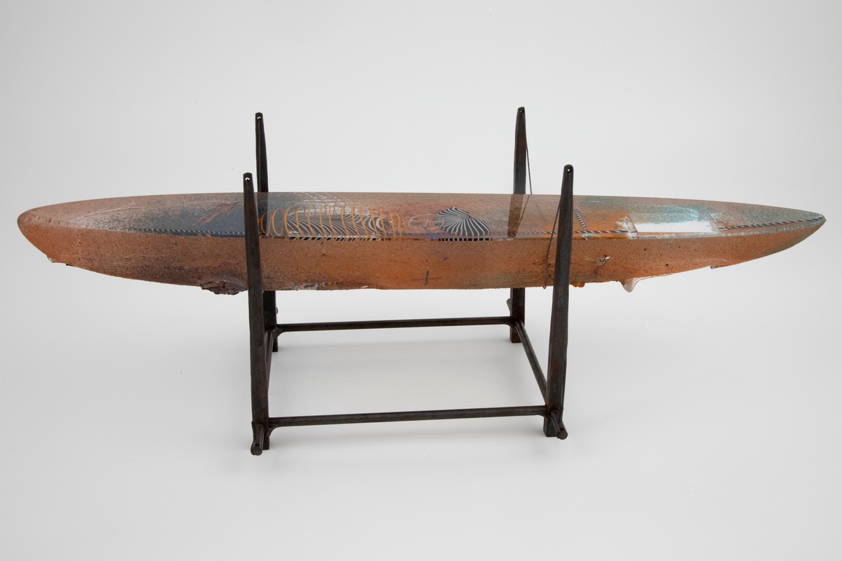 Båtformet skulptur i klart glass, utført ved hjelp av sandstøping. Skulpturens grunnform alluderer til et vikingeskip. De rustrøde sidene har en rustikk overflate, hvor turkisfargede partier tidvis kommer til syne. Inne skulpturen er det innkapslede glass- og metallobjekter, hvis utforming minner om fosiler samt vikingesymboler. Skulpturen bæres av et smijernstativ med fire vertikale pilarer.