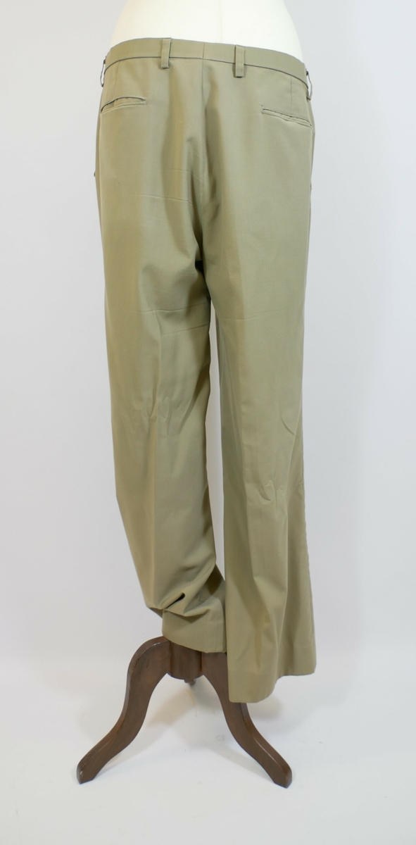 Brun bukse med press. Buksesmekk med glidelås og to metallhekter øverst. To lommer foran og to baklommer. 

