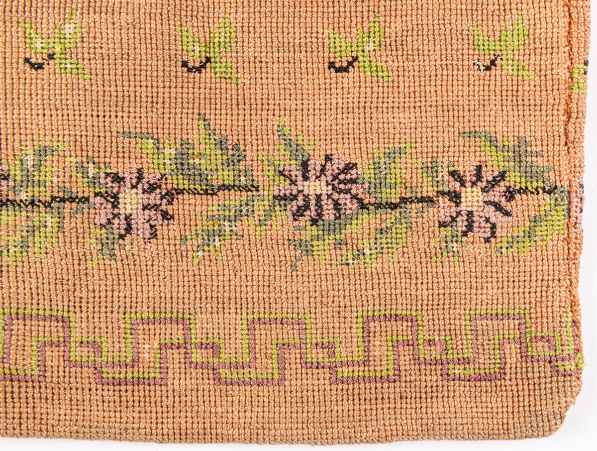 Väska, korsstygnsbroderi i gammalrosa, små blommor och blad strödda, nedtill en ranka i grönt och lila: blommor och blad, nederst en á la greque i grönt och lilka, grönt foder.