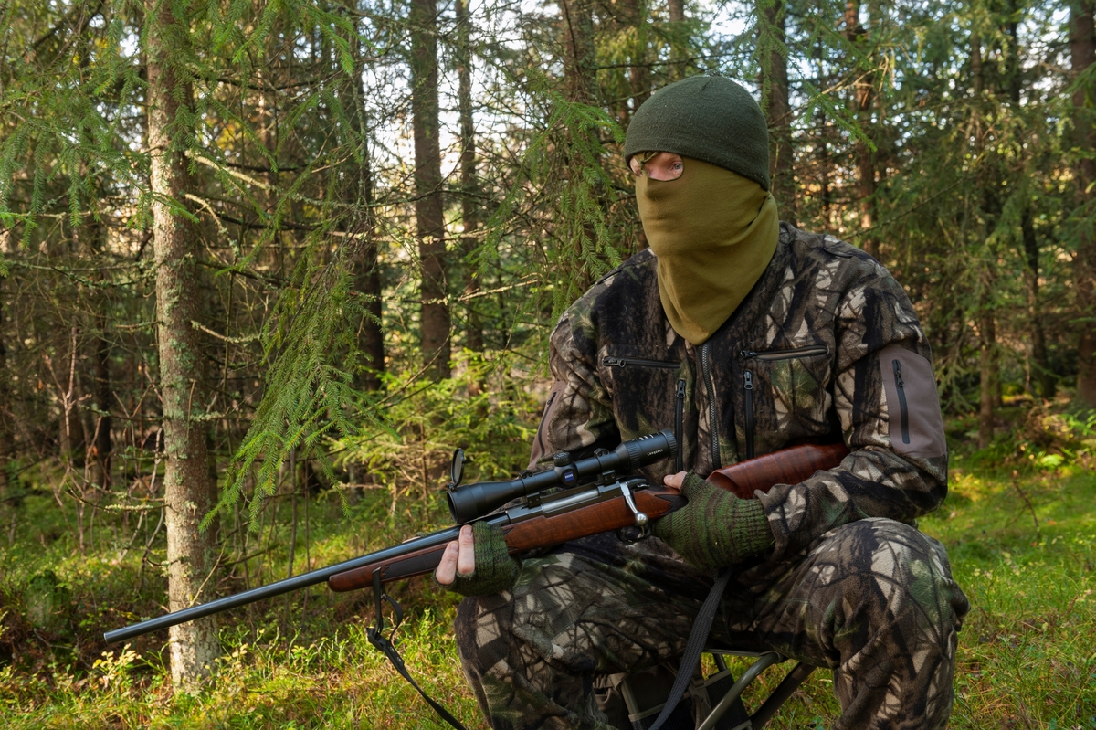 Jeger på post under høstjakta. Posten er plassert nær der man tror viltet kommer, gjerne nær dyrestier eller kjente trekkruter for viltet. Posten er plasseert i tett skog med fri sikt mot åpent terreng. Jegeren bruker en lydløs smygdress av merket Swedish Chasseur Predator Ursus som er utviklet av Rasmus Boström og Jonas Lännbjer. Det finnes også kamuflasjedrakter fra andre produsenter på markedet. Når det er mildt om høsten er det vanlig å sitte uten ansiktsmaske. Jegeren er utstyrt med børse. Han har med seg en jaktradio og Garmin GPS. Jeger: Jan Ove Fuglebrenden fra Løten. Bildet er arrangert. 