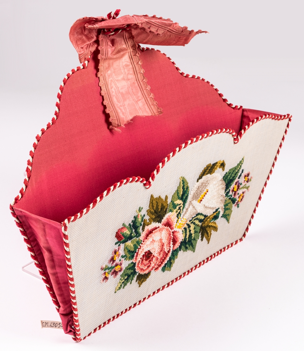 Handskkorg att hänga på väggen, broderad på stramalj, fodrad med rosa siden och kantad med röd och vit snodd.