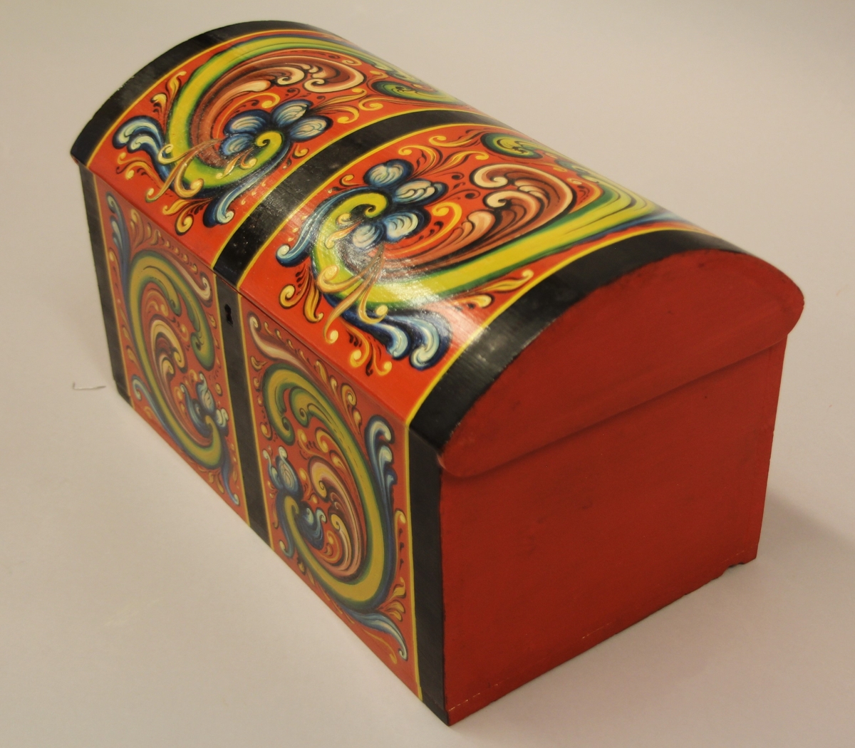 Rosemåla. lita kiste i klare fargar. Tydlege C-krullar både på loket og framme, desse er ramma inn med svarte, måla band.Raud botnfarge. Einsfarga sider og bakside. Umåla under botn. På Baksida er det måla DALEN.  Inni har kista eit lite rom på den eine sida. Grønmåla inni. Kuva lok. Lås med nøkkel.