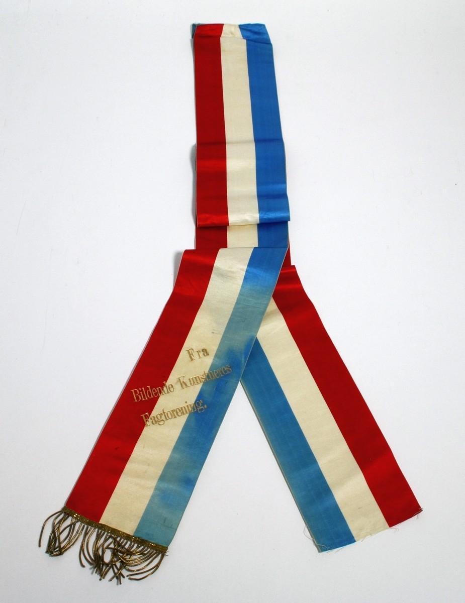 Båresløyfe frå Ivar Aasen si gravferd i 1896. Aasen døydde 23. september 1896, og det var gravferd frå Vår Frelsars gravlund 29. september. (1) På sløyfa står det ei helsing "Fra Bildende Kunstneres Fagforening".

Kjelde:
https://www.sprakradet.no/Vi-og-vart/Publikasjoner/Spraaknytt/Arkivet/Spraaknytt_1996/Spraaknytt_1996_1/Om_Ivar_Aasen_i_eit_minneaar/ (Lesedato: 15.10.2020)