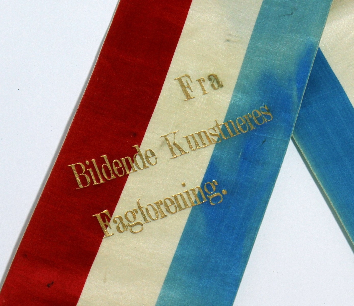 Båresløyfe frå Ivar Aasen si gravferd i 1896. Aasen døydde 23. september 1896, og det var gravferd frå Vår Frelsars gravlund 29. september. (1) På sløyfa står det ei helsing "Fra Bildende Kunstneres Fagforening".

Kjelde:
https://www.sprakradet.no/Vi-og-vart/Publikasjoner/Spraaknytt/Arkivet/Spraaknytt_1996/Spraaknytt_1996_1/Om_Ivar_Aasen_i_eit_minneaar/ (Lesedato: 15.10.2020)