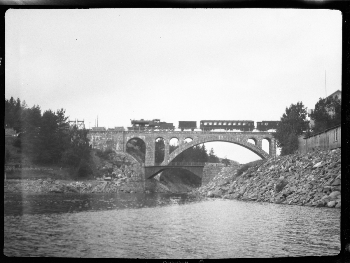 Fotosamling etter Bendik Ketilson Taraldlien (1863-1951) Fyresdal. Gårdbruker, fotograf og skogbruksmann. Fotosamlingen etter fotograf Taraldlien dokumenterer områdene Fyresdal og omegn. 
Landskapsmotiv med tog over steinbru.