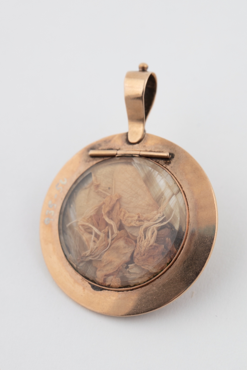 Medaljong med flettet hår og tørkede blomster inni.