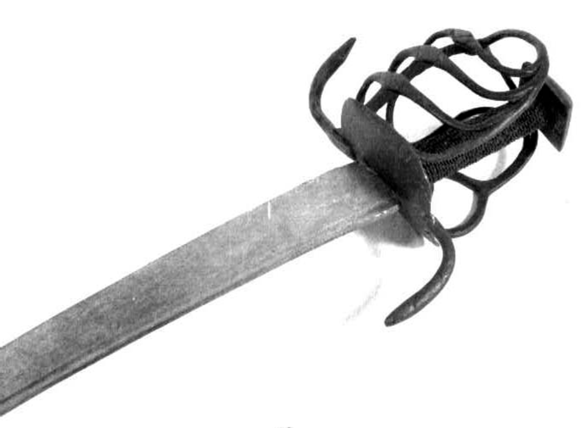 Rund tønneformet knapp i tre. Asymmetrisk feste med tre sidebøyler som har fortykninger på midten på utsiden og tommelbøyle og to sidebøyler på innsiden. Nyreformede parérplater. S-formede runde parérstenger med fortykkede avslutninger på endene. Fremre parérstang er nyere.
Tregrep med jerntrådvikling.
Enegget krum kline med smal ryggstillt blodrand. Smedmerke på venstre side. Klingespissen er dekorert med tre små hull.