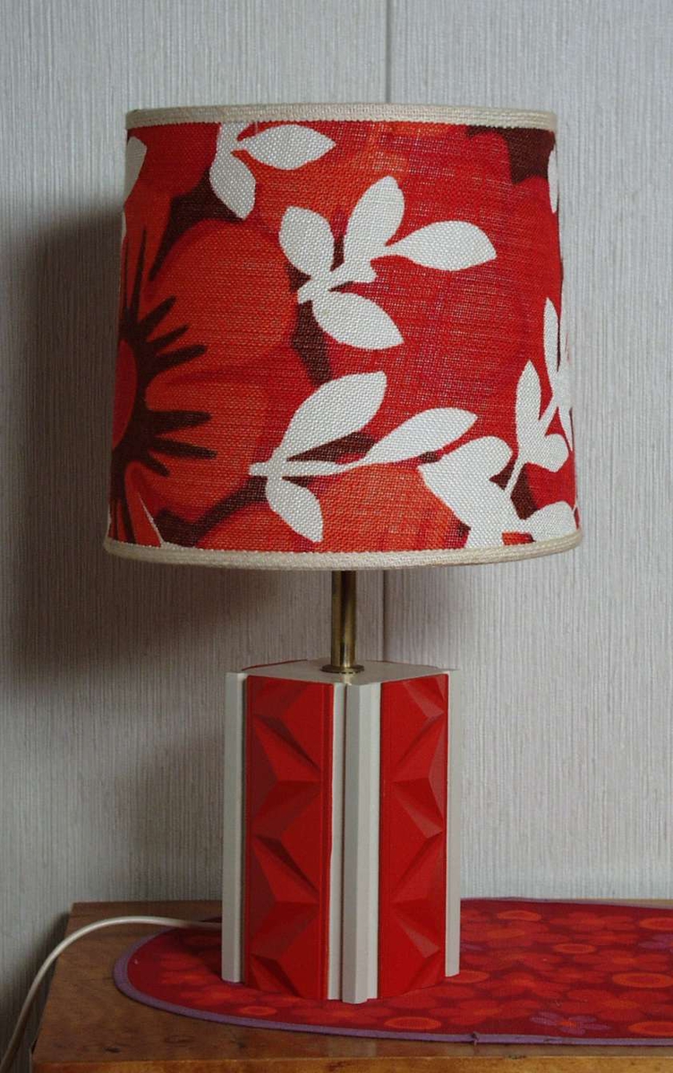Nattbordslampe med firkantet fot i tre og blomstret rød skjerm. 