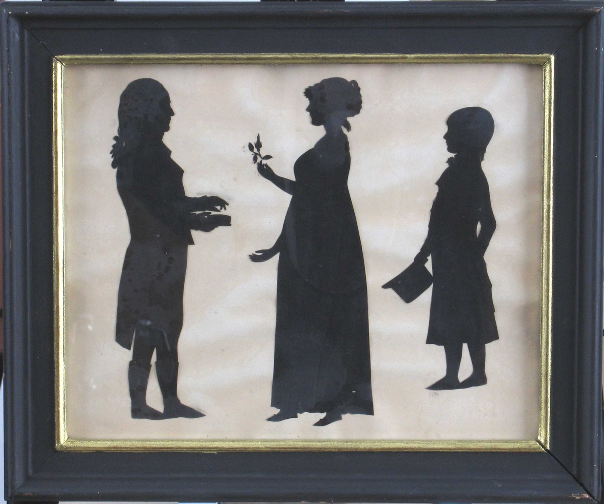 3 personer, stående, helfigur. Silhuett av Peter Andreas Hiorth, 1740 -1817,  (generalmajor, yngste sønn av magister Peder Hiorth og Anna Andersd. Dedekam) med ektefelle (gift 1770)  Birgitte Christine Werner, 1751- 1813, og sønn Peter Andreas Hiorth, 1771 1811, infanterikaptein,  Nannestad.   T.v. general Hiorth prof. h, i piskeparykk, langskjøtet frakk  m. høy krave og brede slag, trange bukser og høye støvler  ("Wertherdrakt"), står m. snusdåse i hånden.  Vendt mot ham, profil v, fru Hiorth, i hånden holder hun  en rosenknopp, iført vid empirekjole m. høyt liv, flate tøysko,  kappe eller høy frisyre på hodet. Helt t. h. m/ profil v.,  sønnen, en halvvoksen gutt: i sid frakk, m. halsbind m. sløyfe, naturlig hår,  børstet frem i pannen, langt i nakken. Holder en  kort, høy stiv hatt i hånden.