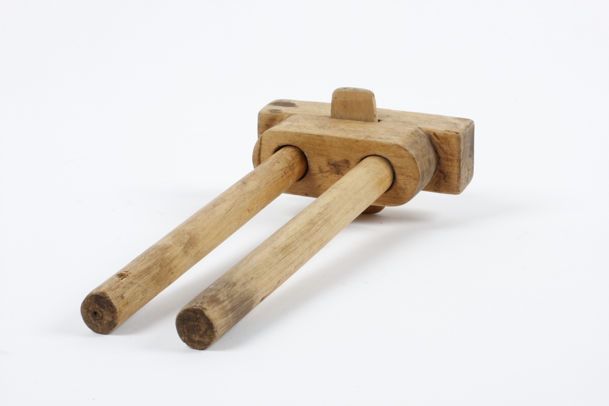 Et stykke med to hol. Gjennom hola to bevegelige, runde pinner med stift til å risse streker med. Trapesformet stykke gjennom hovedstykket mellom pinnene Tidl. reg.:"Strek-mott,  laget av skredder Kristian Braaten (far til O. Braaten) Sløydlærer Pastor Lars Hofgaard"
